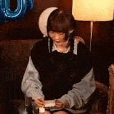 a girl with pigtails is sitting in a chair holding a piece of paper in her hands .