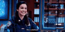 a woman in a police uniform is smiling and talking to a man in a room .