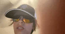 a person wearing a hat with the letter m on it and sunglasses