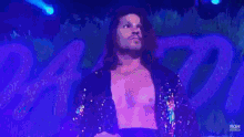 a man without a shirt is standing on a stage in front of a peacock feather wall .