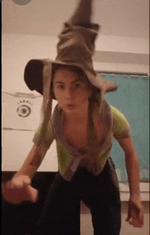 a young girl in a witch costume is standing in a room with a witch hat on her head .