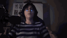 a person wearing glasses and headphones is talking into a microphone .
