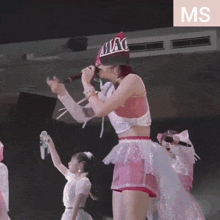 a woman singing into a microphone with the word miac on her hat