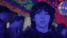 a man with purple hair is standing in front of a disco ball in a dark room