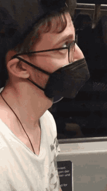 a man wearing glasses and a black mask has a sign on the wall that says serviert