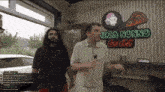 two men are standing in front of a pizza nonno sign