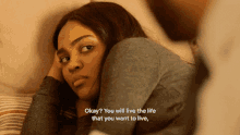 a woman laying on a bed with the words " okay you will live the life that you want to live "