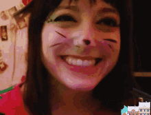 a woman with a cat face painted on her face is smiling