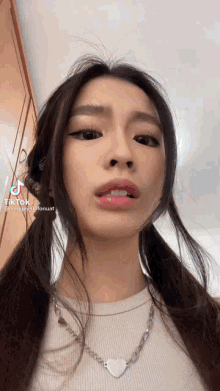 a close up of a woman wearing a white shirt and a necklace .