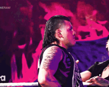 a man with a tattoo on his arm is standing in front of a sign that says ' raw ' on it