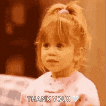 a little girl is saying thank you with a heart in her hand .