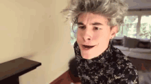 a young man with gray hair is making a funny face in a living room
