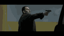 a man in a black jacket is pointing a gun at someone