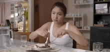 a woman is sitting at a table with a plate of food and a fork and knife .