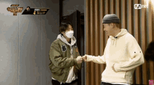 two men shaking hands in front of a mnet banner