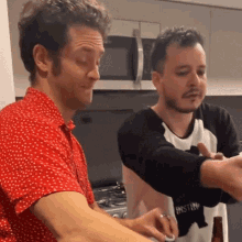 a man in a red polka dot shirt is standing next to another man