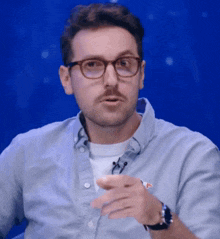 a man wearing glasses and a watch is pointing his finger