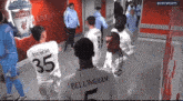 a group of soccer players are standing in a hallway with a liverpool logo on the wall