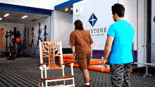 a man in a blue shirt is standing in front of a sign that says ' astone ' on it