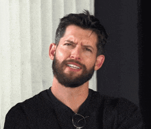 a man with a beard is wearing glasses and making a face