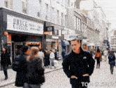 a man walks down a street in front of a store called pryce cameras specialists