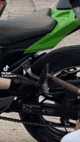 a person is fixing a green motorcycle with a tiktok sticker