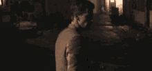 a man is standing in a dark room looking at the camera .