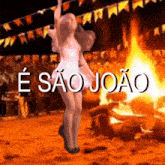 a woman is dancing in front of a fire with the words e sao joao in the background