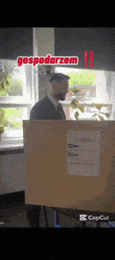a man in a suit and tie stands behind a wooden box with the word gospodarzem on it