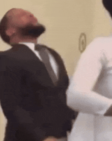 a man in a suit and tie is dancing with a bride in a white dress .