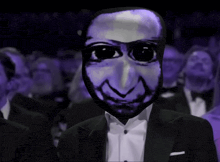 a man in a tuxedo with a purple mask on his face applauds