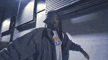 a man with dreadlocks and a hoodie is standing in front of a building .
