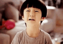 a young boy is crying and making a funny face with his mouth open .
