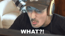 a man wearing headphones and a hat says what on the screen