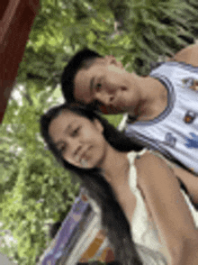 a man and a woman are standing next to each other in a park .