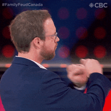 a man in a suit and glasses is giving a fist bump in front of a cbs logo