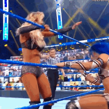 a woman in a wrestling ring with a referee in the background .