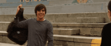 a man in a grey shirt is holding a backpack with the word jansport on the front