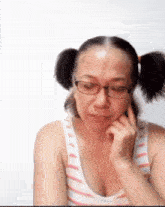 a woman wearing pigtails and glasses is making a funny face