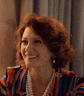 a woman wearing a striped shirt and pearls is smiling