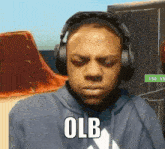 a man wearing headphones is making a funny face and the word olb is on the bottom of his face .