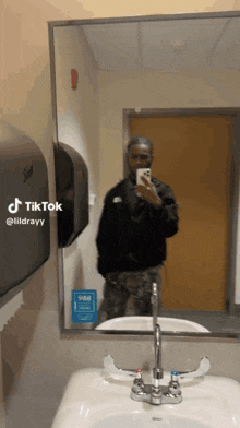 a man taking a picture of himself in a bathroom mirror with a tiktok watermark