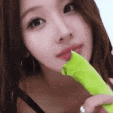 a close up of a woman holding a green object in her mouth .
