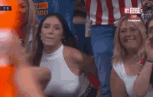 a woman in a white tank top is sitting in a crowd of people watching a soccer game on eleven sports