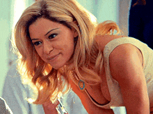 a woman with blonde hair is wearing a plunging neckline tank top and necklace .