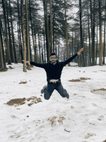 a man wearing sunglasses is jumping in the snow