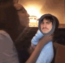 a woman is holding a baby with a fake face on it .