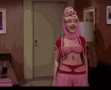 a man in a pink dress is dancing in a living room .