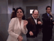 a woman in a white jacket is dancing with two men in suits .