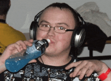 a man wearing headphones drinks from a bottle that says gatorade